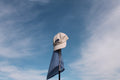 White cap on a flagpole against a blue sky with clouds