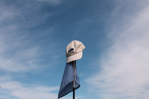 White cap on a flagpole against a blue sky with clouds