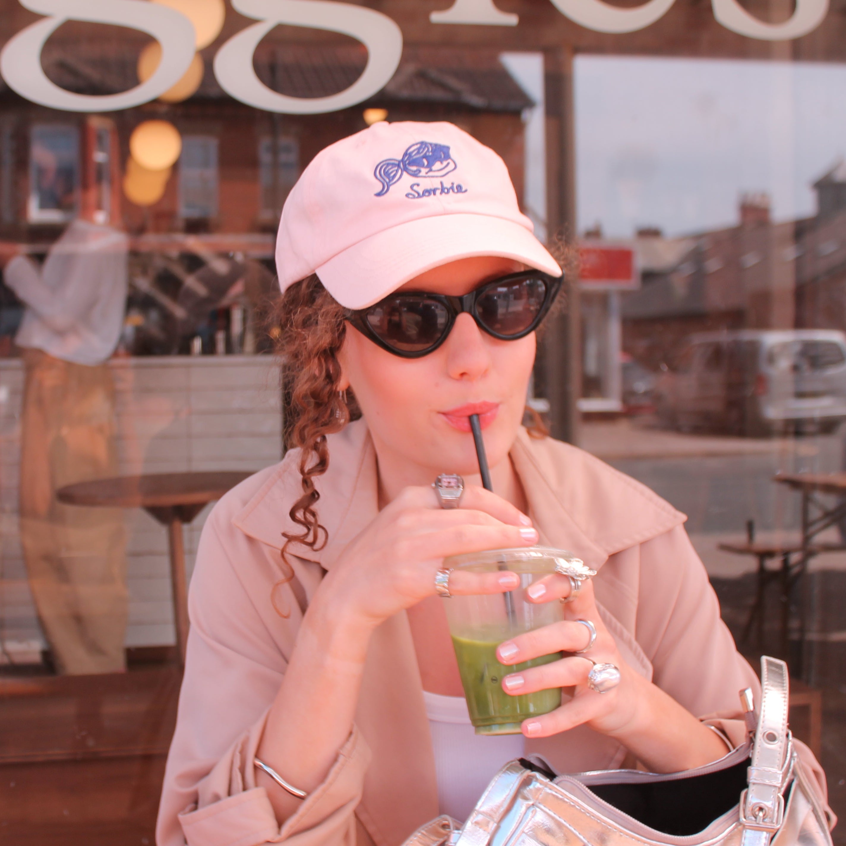 Woman drinking a green beverage through a straw in a casual setting.